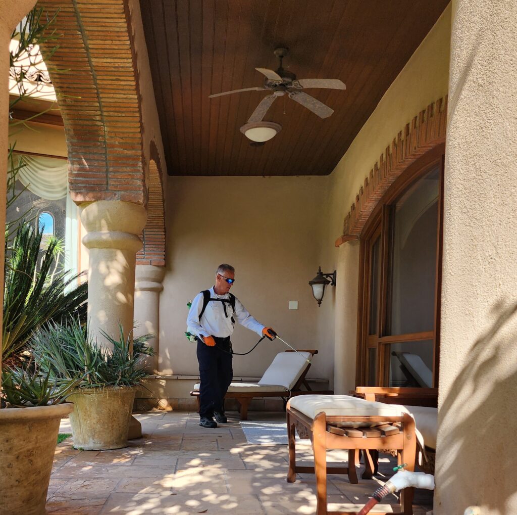 Ozone Pest Control technician treating a home exterior Ozone Pest Control technician spraying the covered patio of a home