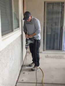 Ozone Pest Control technician drilling into concrete to apply a termite treatment